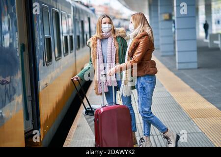 Zwei Frauen am Bahnhof tragen Masken wegen covid-19 Einschränkungen Stockfoto