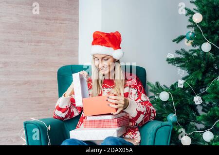 Glückliche junge Frau, die ein Weihnachtsgeschenk-Box öffnet. Stockfoto