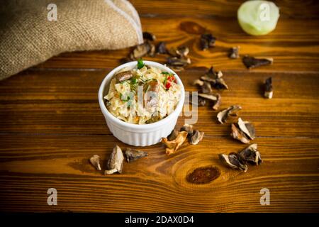 Gekochter Reis mit getrockneten Waldpilzen auf einem Holztisch Stockfoto