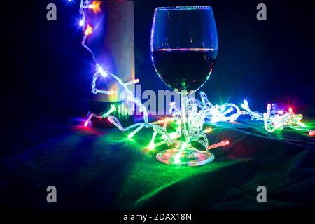 Weinglas und Flasche in glänzendem Girlande Bokeh auf schwarz Hintergrund Stockfoto