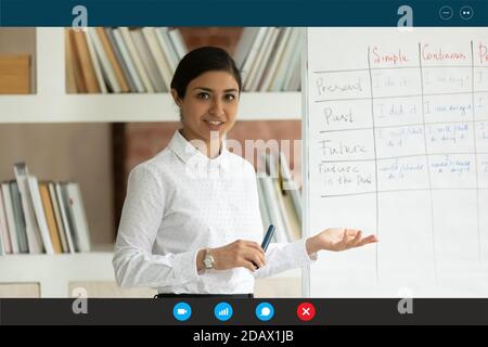 Lächelnder junger indischer Tutor, der Fremdsprache fernab unterrichtet. Stockfoto