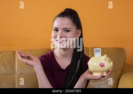 Das erste eingesparte Geld, auch das kleinste, gibt Anlass, glücklich und stolz zu sein. Ein junger Erwachsener spart erfolgreich und investiert das verdiente Geld. Stockfoto