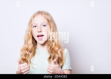 Daumen nach oben von einem Pre-teen Mädchen mit blauen Augen. Flacher Freiheitsgrad - Fokus auf das linke Auge des Modells. Stockfoto