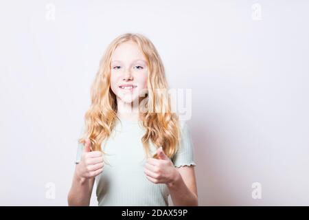 Daumen nach oben von einem Pre-teen Mädchen mit blauen Augen. Flacher Freiheitsgrad - Fokus auf das rechte Auge des Modells. Stockfoto