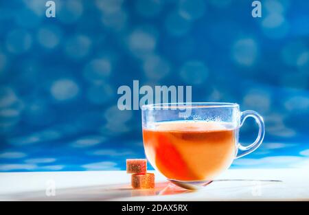 Tasse heißen Tee mit Shugar und Teelöffel auf blauem Hintergrund. Stockfoto