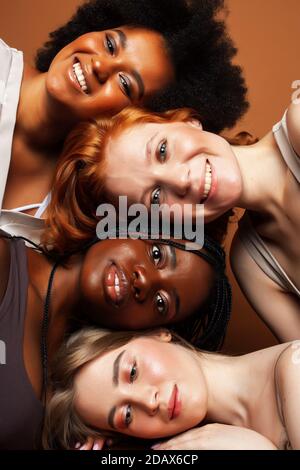 Junge hübsche kaukasische, afro, skandinavische Frau posiert fröhlich zusammen auf braunem Hintergrund, Lifestyle diverse Nationalität Menschen Konzept Stockfoto