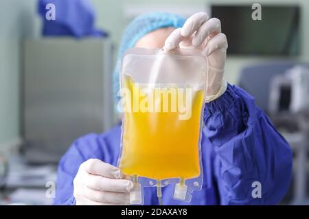 Handschuhen eines Arztes, der eine Tüte hält Blutplasma Nahaufnahme Stockfoto