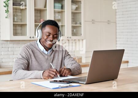 Schwarzer Student mit elearning-Kopfhörern auf Laptop im Heimbüro. Stockfoto