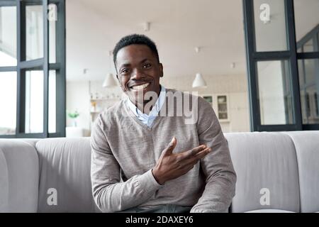 Glücklich afrikanischen schwarzen jungen Mann Blick auf Kamera sitzen auf Couch zu Hause. Stockfoto