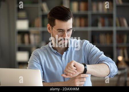 Der Geschäftsmann schaut auf die Armbanduhr und überprüft die Zeit am Arbeitsplatz Stockfoto