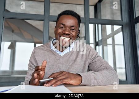 Fröhlicher afrikanischer Geschäftsmann im Gespräch mit Web-Cam während der Konferenz. Stockfoto