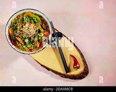 Schüssel mit japanischer Ramen-Suppe mit gebratenem Lachs mit dunklen Soba-Nudeln. Suppe aus schmackhaftem Fischbarsch mit Stücken gebratenem Lachs, Kirschtomaten, Lch Stockfoto