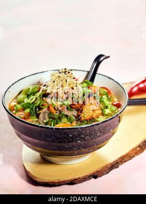 Schüssel mit japanischer Ramen-Suppe mit gebratenem Lachs mit dunklen Soba-Nudeln. Suppe aus schmackhaftem Fischbarsch mit Stücken gebratenem Lachs, Kirschtomaten, Lch Stockfoto