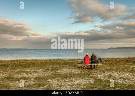 Älteres Ehepaar, das allein auf einer Bank am Strand vor dem Meer sitzt, Dänemark, 15. November 2020 Stockfoto