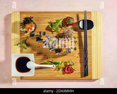 Lachs California Maki Rolle. Aus rohem Lachsfisch, Avocado, grünem Salat und Philadelphia Käse in Nori gerollt. Garniert mit gelbem und rotem Kaviar. Stockfoto