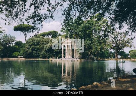 Panoramablick auf den Tempel des Asklepios (Tempio di Esculapio) und See in den öffentlichen Park der Villa Borghese. Tag Sommer und blauer Himmel Stockfoto