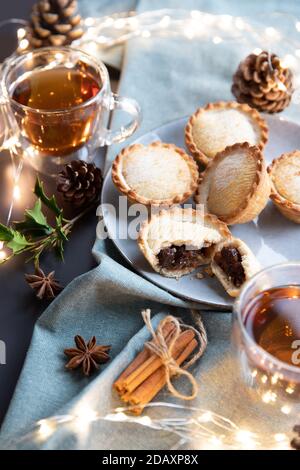 Pasteten auf einem Teller mit schwarzem Tee serviert. Ein Mince Pie ist ein traditioneller Weihnachtskuchen, gefüllt mit einer Mischung aus getrockneten Früchten und Gewürzen. Stockfoto