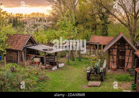 Schöner Bauernhof mit Ziegel und Fachwerk Gebäude und Traktor an Abend Stockfoto