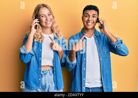 Junge interracial paar mit Gespräch auf dem Smartphone lächeln Glücklich zeigen mit Hand und Finger Stockfoto