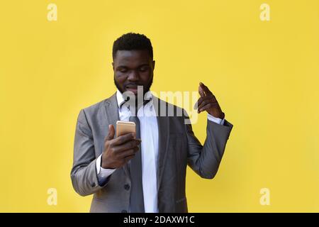 Der Afroamerikaner auf einem gelben Hintergrund mit einem Telefon, gewann Stockfoto