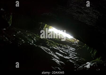 Höhlenforscher, die sich der Spitze des Seils nähern, klettern in der klaffenden Schlucht von Eldon Hole, einer vertikalen Höhle in der Nähe von Castleton, Derbyshire. Der Schacht ist 60 Meter tief. Stockfoto