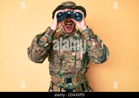 Junger Kaukasier in Tarnuniform mit Ferngläsern wütend und verrückt schreien frustriert und wütend, schreien mit Wut aufschauen. Stockfoto