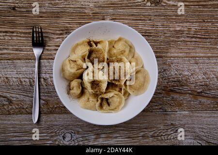 Teller mit hausgemachten russischen Knödel auf einem Holztisch und Eine Gabel daneben Stockfoto