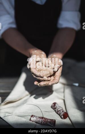 Nahaufnahme der Frau Hände arbeitet mit Ton. Weibliche Töpfer knetet und befeuchtet den Ton vor der Arbeit. Stockfoto
