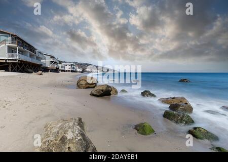 Häuser am Meer mit Bewegung verschwimmen Wasser und bewölktem Himmel am Carbon Beach in Malibu, Kalifornien. Stockfoto