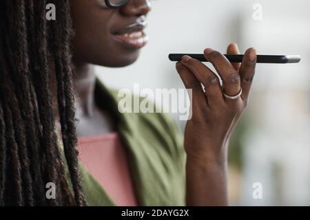 Nahaufnahme Porträt der stilvollen jungen afrikanischen Frau Aufnahme Sprachnachricht über Smartphone im Büro, Kopierraum Stockfoto