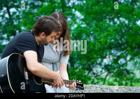 Bruder lehrt Schwester Gitarre in der Natur zu spielen Stockfoto