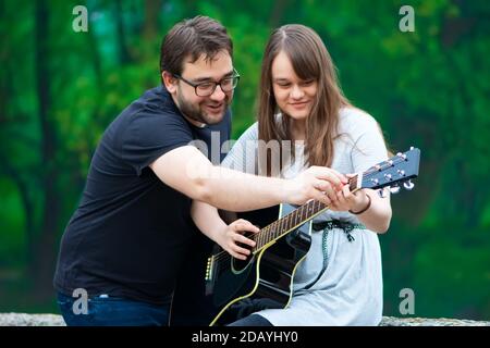 Bruder lehrt Schwester Gitarre in der Natur zu spielen Stockfoto