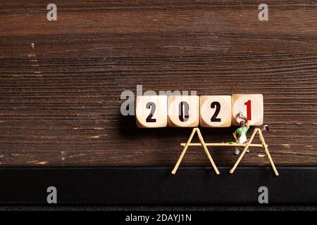 Kleine Malerfiguren und Botschaft 2021 auf Holzwürfeln in Vorderseite von Holzhintergrund Stockfoto