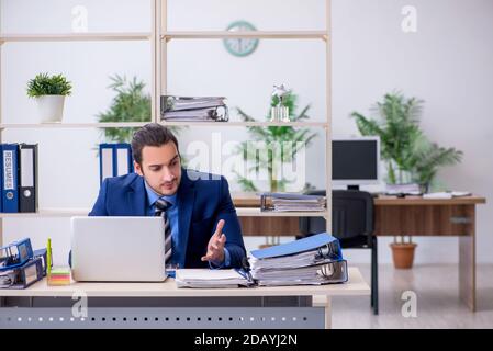 Junge männliche Mitarbeiter mit übermäßiger Arbeit unzufrieden Stockfoto