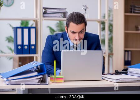 Junge männliche Mitarbeiter mit übermäßiger Arbeit unzufrieden Stockfoto