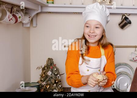 Kleines Mädchen macht Weihnachten Lebkuchen in der Küche im dekorierten Wohnzimmer. Backen und Kochen mit Kindern zu Weihnachten zu Hause. Stockfoto