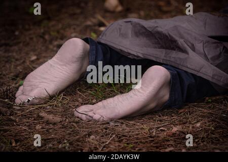 Barfuß Leiche im Wald. Mordopfer auf dem Boden im Wald liegend. Ermordete Bürger, Tatort Stockfoto