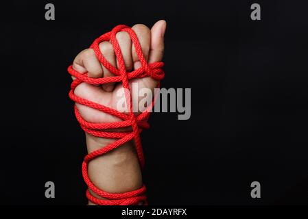 Frau Hand gefesselt mit Seil auf schwarzem Hintergrund, Menschenhandel und Missbrauch, Internationaler Tag der Menschenrechte Stockfoto