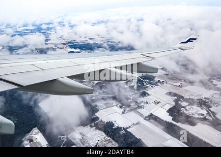 Flügel und Logo der Finnair-Fluggesellschaft mit dem Flugzeug, das über die finnische Landschaft fliegt Stockfoto