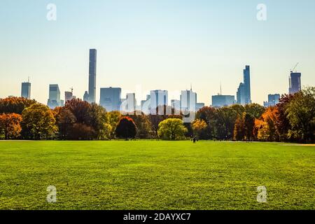 Der Central Park im Herbst mit Touristen genießen den Tag Mit Skyline von Manhattan und gelb-roten Blättern, die ihre Farbe ändern Auf dem Höhepunkt der Herbstsaison Stockfoto