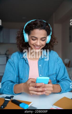 Vertikales Porträt einer jungen Frau in Kopfhörern mit Smartphone-App. Stockfoto