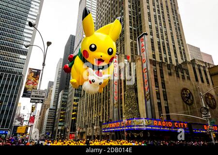 Pikachu pokemon Ballon schwebt in der Luft während der Macy's Thanksgiving Day Parade entlang der Avenue of Americas mit Radio Music Hall im Hintergrund. Stockfoto