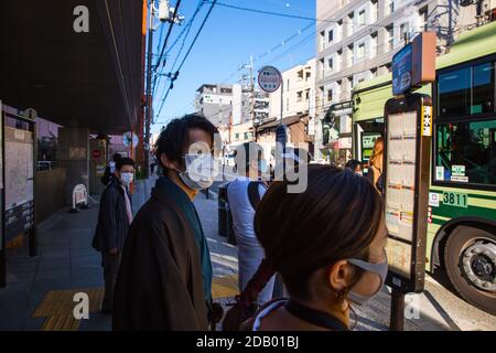 Kyoto, Japan. November 2020. Touristen mit Gesichtsmasken und traditionellen japanischen Outfits warten an einer Bushaltestelle im Kiyomizu-Viertel. Kredit: SOPA Images Limited/Alamy Live Nachrichten Stockfoto