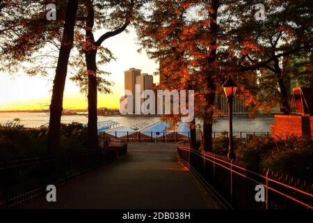 Der Blick auf Lower Manhattan von der Brooklyn Heights Promenade an einem schönen Herbstabend mit roten und gelben Bäumen und warmem Sonnenuntergangslicht. Stockfoto