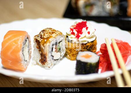 Japanisches Sushi-Essen. Maki und Brötchen mit Thunfisch, Lachs, Garnelen, Krabben und Kaviar. Draufsicht auf verschiedene Sushi in weißem Teller. Stockfoto