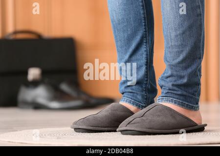 Die Beine des Mannes tragen Hausschuhe im Flur. Konzept des Tages frei Stockfoto