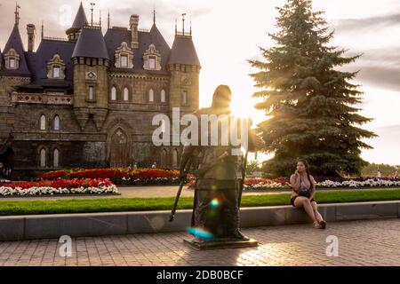 Khryashchevka, Russland, 16. Juli 2020, Mädchen vor dem Hintergrund der Burg und Statue des Ritters, Hintergrundbeleuchtung fotografiert Stockfoto