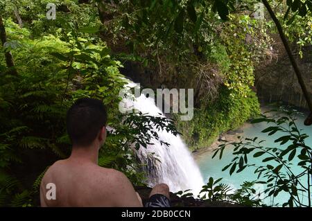 Guy sitzt auf den Kawasan Falls in Cebu, Philippinen Stockfoto