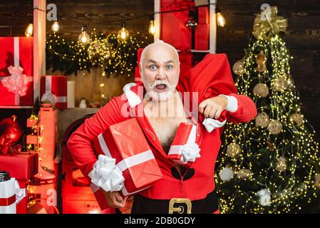 Startseite Einbrecher Weihnachtsmann in einer Maske ins Haus. Lustige böse Weihnachtsmann mit Geschenk, Tasche mit Geschenken. Santa in der Maske mit Tasche Stockfoto