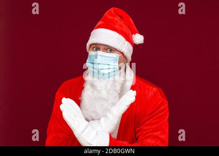 Nahaufnahme weihnachtsmann Kostüm Ablehnung Ausdruck Kreuzung Arme und Handflächen tun negative Zeichen, trägt medizinische Maske.Vorderansicht Bild. Stockfoto